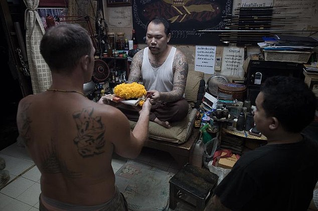 A German tourist makes a ritual offering before Thai master tattoo artist Ajarn Neng at his studio in Bangkok