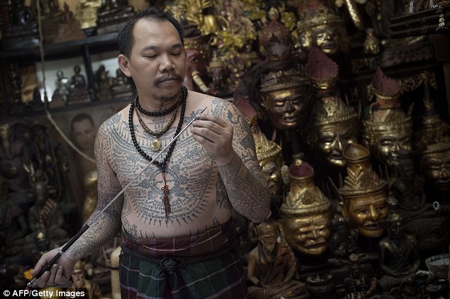 A German tourist makes a ritual offering before Thai master tattoo artist Ajarn Neng at his studio in Bangkok