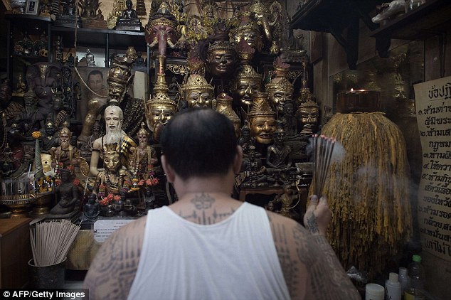 Thai master tattoo artist Arjarn Neng prays in front of a shrine at his studio in Bangkok