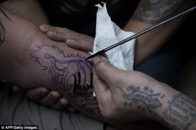 A German tourist makes a ritual offering before Thai master tattoo artist Ajarn Neng at his studio in Bangkok