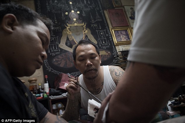 Thai master tattoo artist Arjarn Neng tattoos a German tourist at his studio in Bangkok