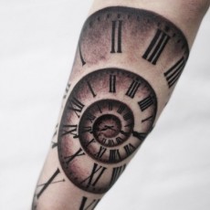 Татуировка на предплечье девушки - спиральные часы